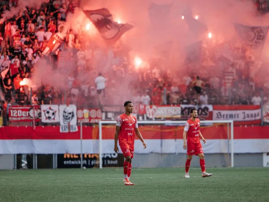 Fußballspieler vor dem Gästeblock mit Pyrotechnik, Fußballfotografie von aLx-design
