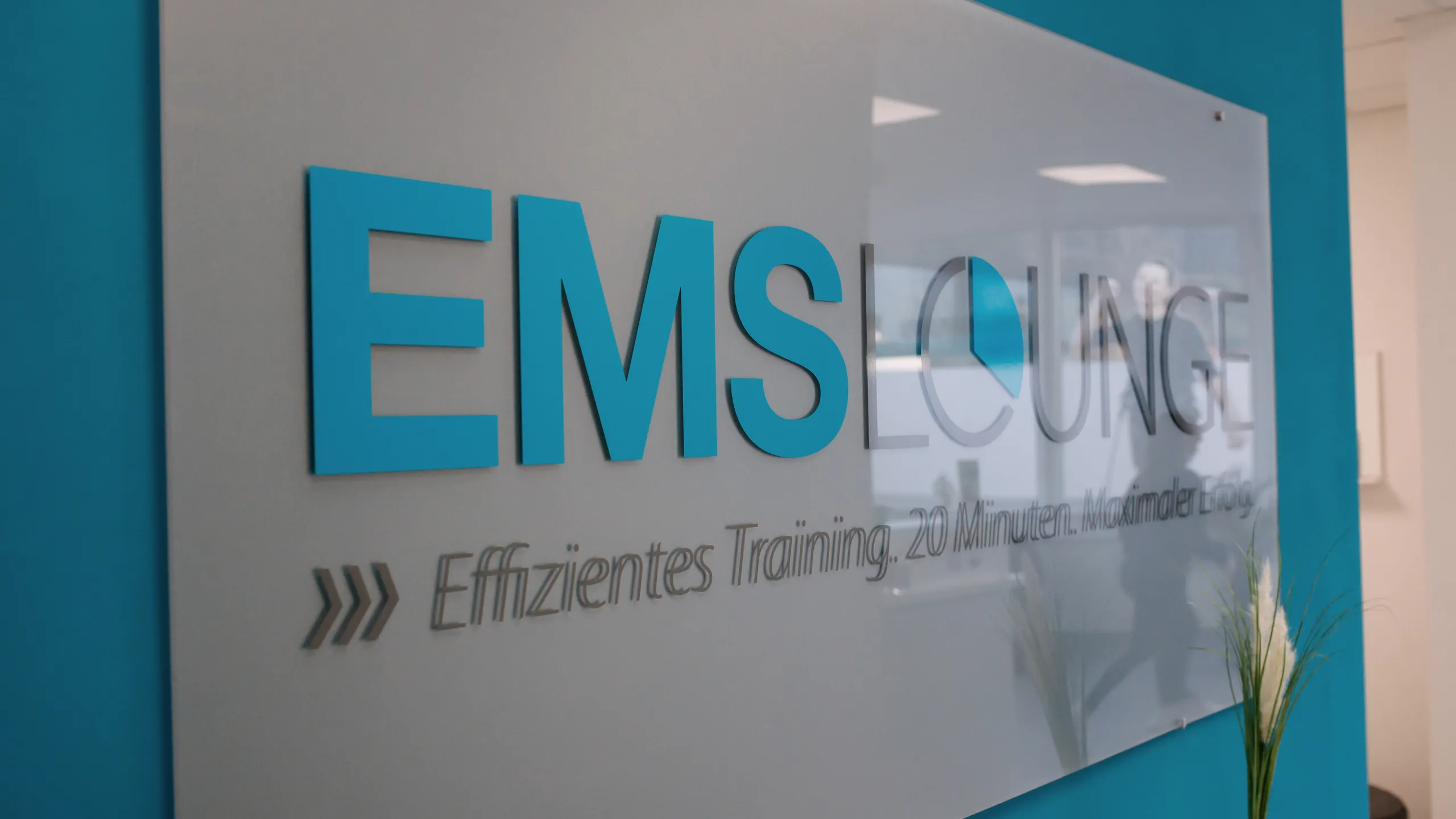 Empfangsbereich der EMS Lounge mit Logo an der Wand, Businessfotografie von aLx-design